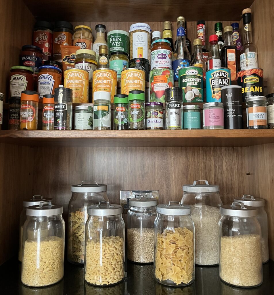 Organised pantry shelves with labeled clear containers and jars