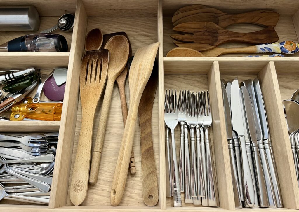 Organised kitchen drawers with dividers and utensils for efficient storage