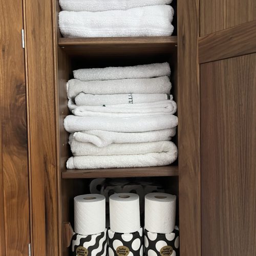 bathroom cupboard with towels and toilet paper