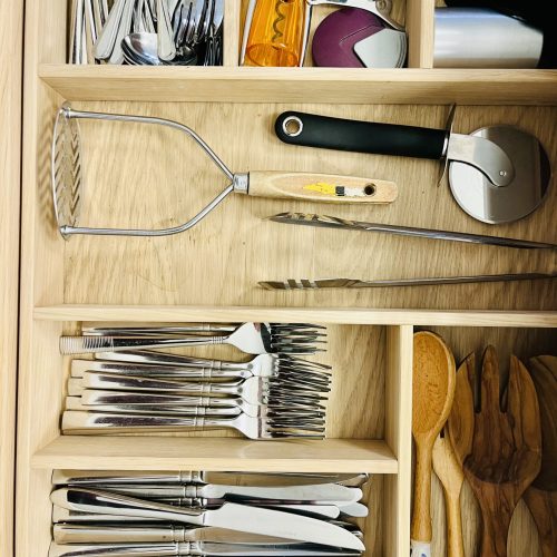 Organised kitchen drawers with dividers and utensils for efficient storage